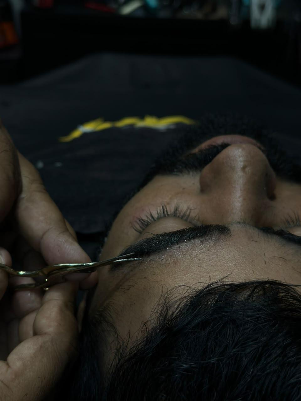 Barbeiro detalhando sobrancelha e barba